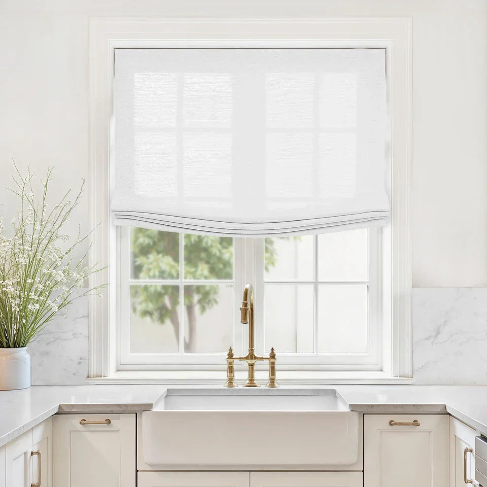 Modern kitchen with a window above a sink, featuring a gold faucet and white blinds.