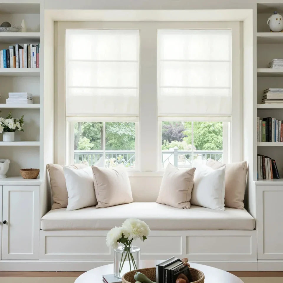 Cozy window seat with cushions in a room with bookshelves and a view of greenery outside.