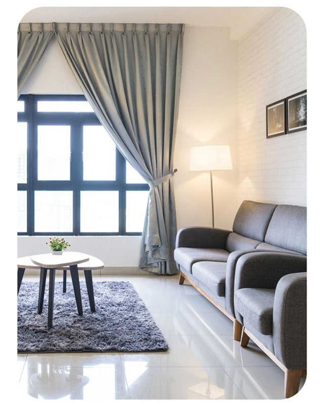 Modern living room with gray sofa, curtains, and lamp.