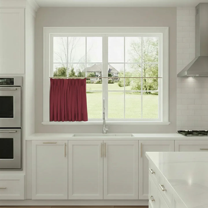 Modern kitchen with white cabinets, a window, and a red curtain.